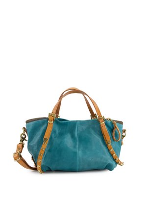 Niebieska skórzana torebka z jasnobrązowymi skórzanymi uchwytami, regulowanym paskiem, mosiężnymi ćwiekami i zamkiem błyskawicznym na białym tle.