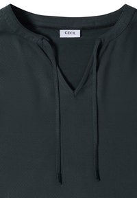 T-shirt vert foncé col V avec cordons et une étiquette blanche indiquant "CECIL" à l'intérieur du col.