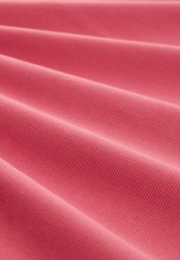 Textile avec un tissage texturé dans une teinte rose vif, présentant des ondulations et des plis, mettant en valeur sa surface lisse et légèrement surélevée.
