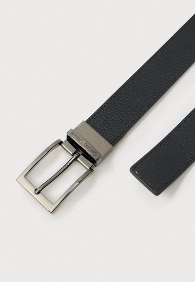 Μαύρη δερμάτινη ζώνη με λεία υφή, με ασημένια μεταλλική αγκράφα σε σχήμα τετραγώνου και καρφί για στερέωση.