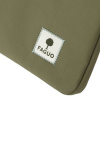 Olegrüner Stoff mit einem weißen, gestickten quadratischen Patch, der ein Baum-Icon und das Wort "FAGUO" in dunkler Schrift zeigt.