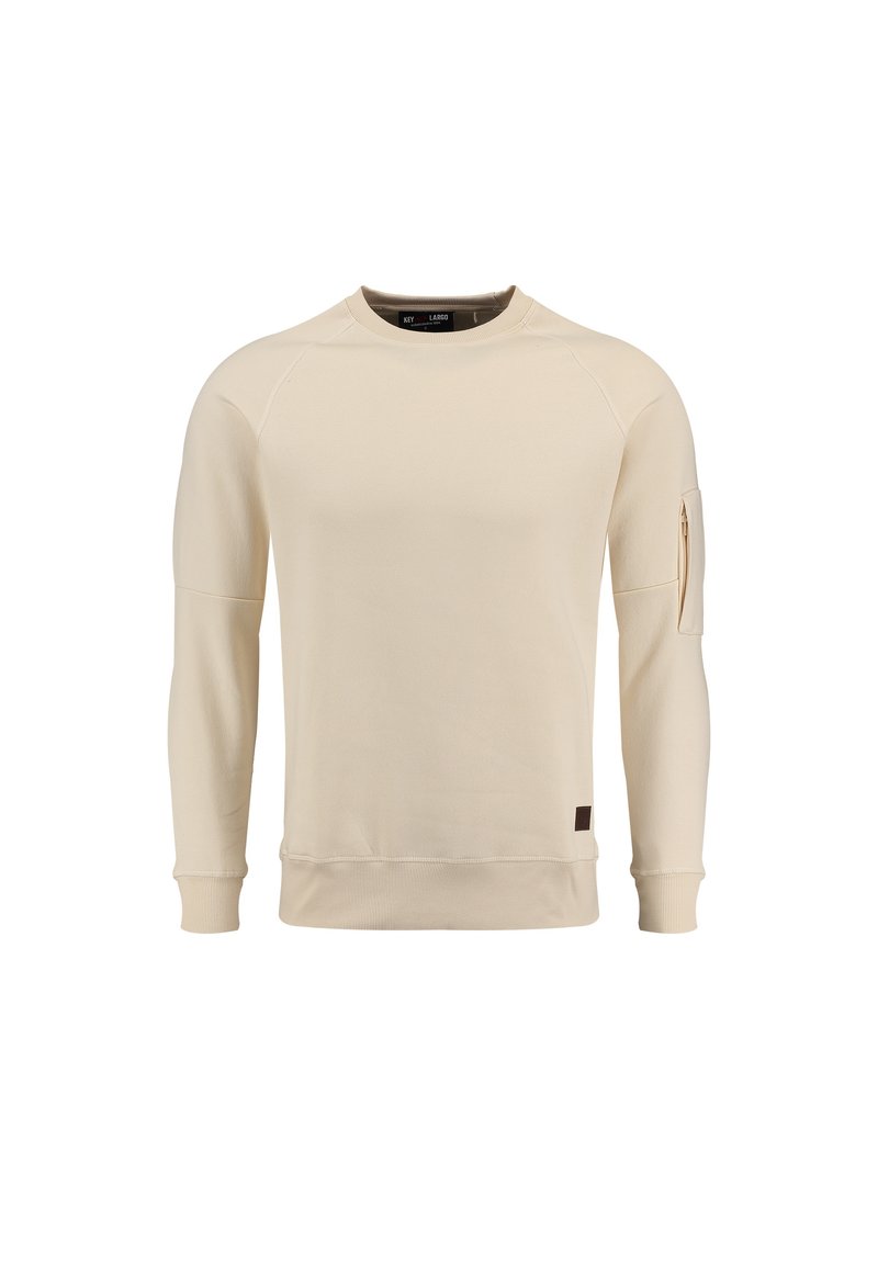 Sudadera color beige claro con puños y bajo acanalados, que presenta un bolsillo con cremallera en la manga y un pequeño parche de logo marrón en el lado.