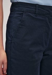Pantaloni blu navy realizzati in tessuto morbido, dotati di una vestibilità dritta, tasche laterali e una texture liscia con dettagli di cucitura minimi.