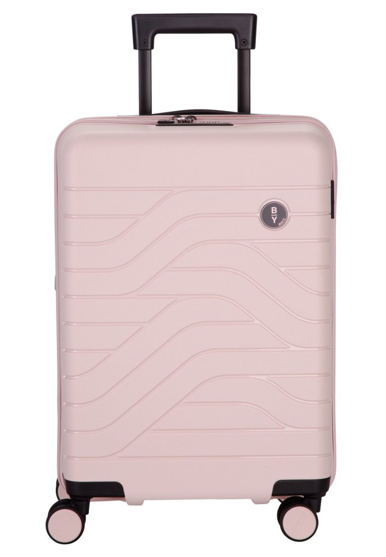 Valigia rigida rosa con un design testurizzato ondulato, manico retrattile nero e quattro ruote multidirezionali per una facile mobilità.