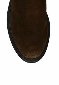 Bruine suède schoen met een ronde neus en een contrasterende zwarte rubberen zool, met een gladde textuur en minimale details.