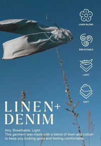 Jean en denim bleu clair suspendu devant un ciel bleu clair avec des tiges de plantes et un texte mettant en avant le mélange de lin, la respirabilité, la légèreté et la douceur du tissu.