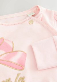 Heled roosa puuvillane topp kuldsete aktsentidega. Omab kõverat kaelust, tikitud ribakujundust ja nööpklambrit. Pehme tekstuur.