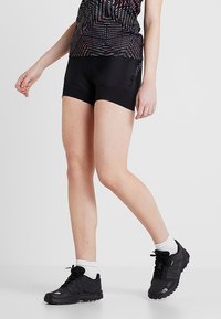 Black athletic shorts made of a stretchy material with a fitted design. Paired with black sports shoes and white ankle socks.