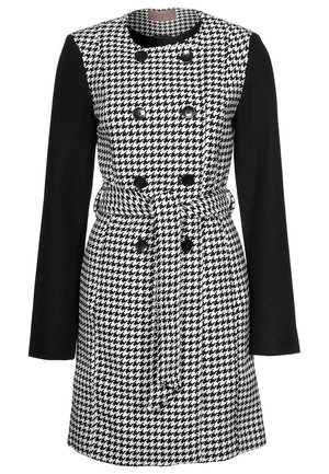 Manteau à motif pied-de-poule noir et blanc avec manches longues noires, boutons croisés et ceinture assortie à la taille.