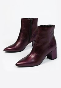 Bottes chelsea en cuir bordeaux avec un bout pointu, fermeture éclair sur le côté et talon bloc. Texture lisse avec une finition brillante.