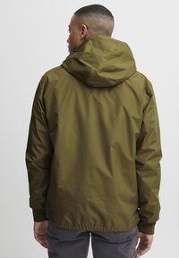 Olive green waterproof jacket with a hood, elastic cuffs, and a cinched waist, made from smooth, lightweight material.