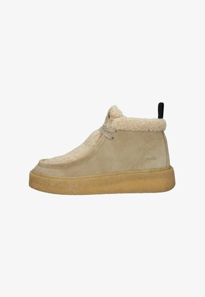 Stivale alla caviglia in suede beige con un colletto soffice color crema, allacciatura frontale e una suola spessa e testurizzata in gomma. Branding sul lato vicino al tallone.
