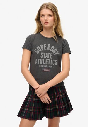 Grå t-shirt med "Superdry State Athletics" print, parret med en plisseret grønternet nederdel med røde og gule detaljer.