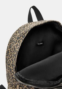 Rucsac cu imprimeu de leopard maro, cu interior negru și închidere cu fermoar. Include o etichetă mică a brandului în interior.