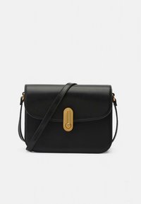 Mala preta de couro tipo tiracolo com aba frontal e ferragens douradas. Apresenta um fecho geométrico e uma alça ajustável única.