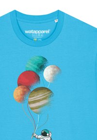 T-shirt turquoise avec un astronaute tenant cinq ballons en forme de planète. L'illustration montre des planètes de différentes couleurs et textures.