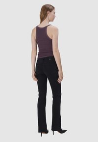 Zwarte uitlopende spijkerbroek en een aansluitend paarse tanktop. De spijkerbroek heeft een gladde textuur en beschikt over zakken, terwijl de tanktop een eenvoudig ontwerp heeft.