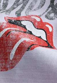 Punaiset huulet -kuvio valkoisella kankaalla, jossa musta ääriviiva ja valkoisia korostuksia. Teksturoitu painatus, jolla on vintage-ilme.