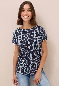 Marinblå och ljusblå mönstrad t-shirt gjord av mjukt material, med lös passform, rund halsringning och korta ärmar.