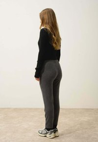 Svart ribbad tröja kombinerad med grå tajta sweatpants som har en mjuk textur. Svart och grå träningsskor med vita detaljer fulländar stilen.