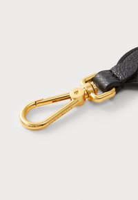 Cinturino in pelle nera con un fermaglio metallico dorato. Il fermaglio presenta un design curvo con una finitura lucida e una incisione del marchio ben visibile.