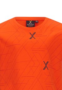 Heldere oranje T-shirt met een geometrisch patroon en blauwe tekst, gemaakt van zacht materiaal met een ronde hals. Retourlabel zichtbaar.