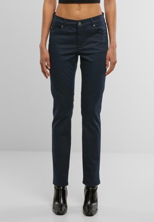 Marineblå jeans med slim fit, fem-lommers design, metallknap lukning og let stræk. Sættes sammen med sorte højhælede ankelstøvler.