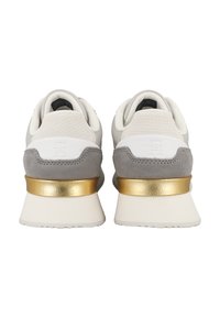 Sneaker grigio e bianco con texture e un accento metallico dorato sul tallone. Presentano un mix di materiali lisci e scamosciati. Forma arrotondata.