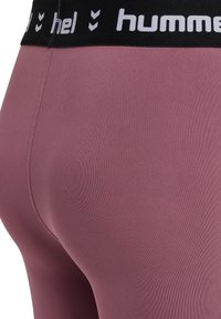 Hoogwaardige leggings in mauve stof met een gladde textuur. Voorzien van een zwarte elastische tailleband met een wit merlogo en chevronaccenten.
