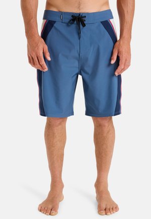 Blaue Badeshorts mit einem Zugbandbund, seitlichen Streifen in Marineblau und Rot sowie einem leichten, glatten Stoff. Die Länge reicht bis zur Mitte des Oberschenkels.