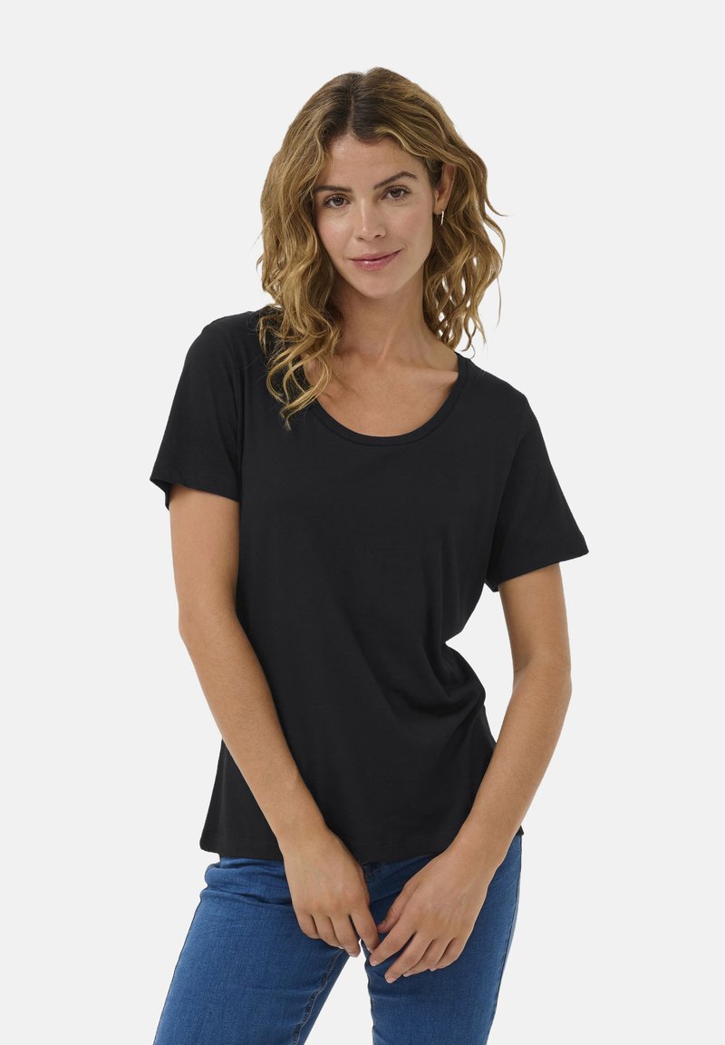 Čierne tričko s krátkym rukávom a okrúhlym výstrihom, vyrobené z mäkkej tkaniny. V kombinácii s modrými džínami, ktoré majú uvoľnený strih.