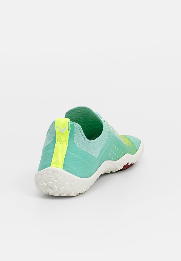 Zapatilla deportiva turquesa con parte superior de malla transpirable y lengüeta trasera amarilla. Presenta una suela blanca texturizada con acentos rojos. Forma redondeada.