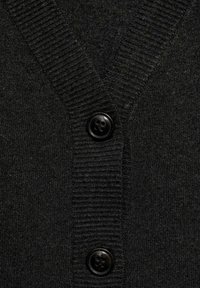 Gros plan d’un cardigan tricoté noir à côtes avec un col en V et deux gros boutons noirs fixés sur la patte de boutonnage avant.