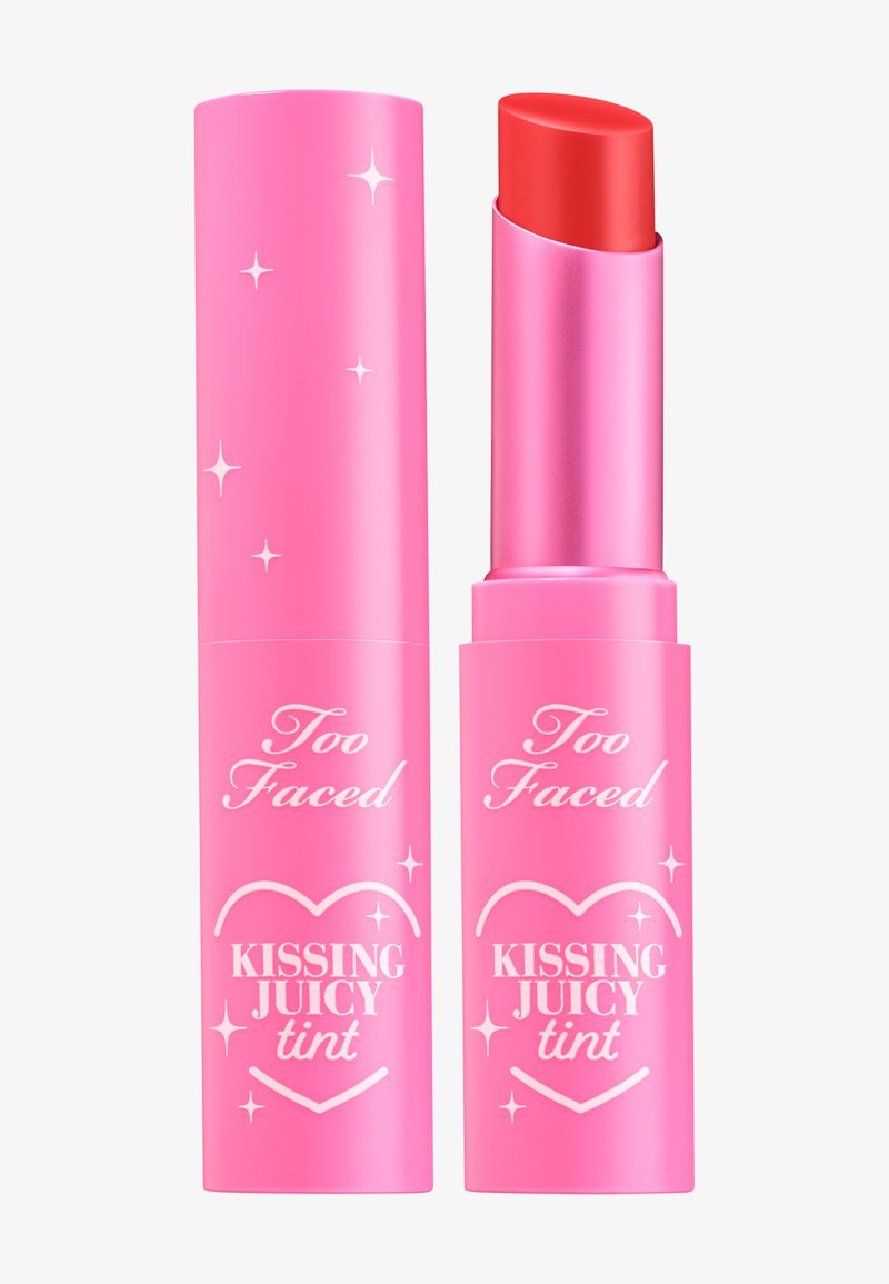 Too Faced Kissing Juicy Tint in een helderrode huls, verpakt in een glanzende roze tube versierd met witte sterren en merktekst.