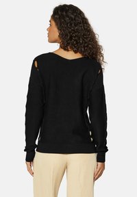 Schwarzer Strickpullover mit weitem Ausschnitt und Ausschnittdetails an den Ärmeln, ausgestattet mit einem gerippten Bund und strukturiertem Stoff.