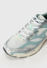 Lightweight running shoe featuring a mesh upper in silver and mint green, with white laces and a textured rubber sole. Notable silver accents.