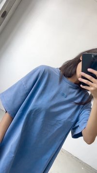 Niebieska, oversize koszulka z bawełny, z krótkimi rękawami i okrągłym dekoltem. Dyskretne logo na piersi. Gładka tekstura.