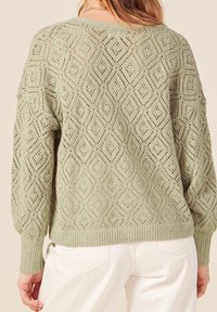 Jasnozielony sweter z dzianiny z wzorem rombowej kratki, ściągaczami na mankietach i dolnym brzegu, o luźnym kroju i teksturowanym wykończeniu.