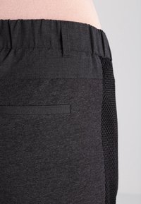 Shorts de sport noirs dotés d'un panneau latéral en maille texturée, d'une taille plate et d'une petite poche arrière pour le rangement.