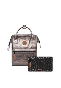 Metallisch silberner Rucksack mit einem Obergriff, einer vorderen Reißverschlusstasche und braunen Akzenten, kombiniert mit einer schwarzen Tasche mit einem Leopardenmuster.
