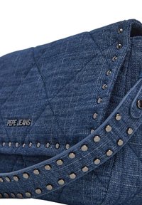 Džinsinis per petį nešiojamas krepšys su siuvinėtu raštu, mėlynos spalvos, ir metaliniais smeigėmis prie diržo. Yra juodas „Pepe Jeans“ logotipas.