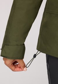 Waterdichte groene jacksleeve met een manchet en verstelbaar trekkoord. Gladde textuur, functionele hardwaredetails zichtbaar.