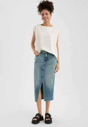 White, short-sleeve top paired with a light blue denim midi skirt featuring a front slit. Black platform sandals complete the outfit.