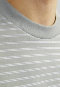 Halli triibuline T-särk pehme puuvillase tekstuuriga, millel on valged horisontaalsed triibud ja ribaga ümar kaelus. Puhtad ja lihtsad detailid.