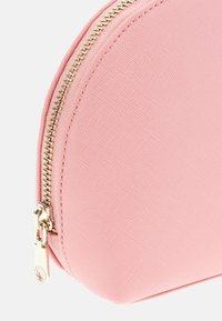 Tasca rosa con parte superiore arrotondata, tessuto texturizzato, dettaglio della zip dorata e un piccolo accessorio in metallo a forma di lucchetto.