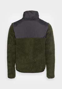 Chaqueta de forro polar con un cuerpo verde texturizado y una parte superior lisa de nylon negro, con un alto cuello y mangas largas.