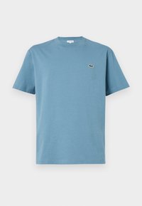 T-shirt uni bleu à manches courtes avec col rond et petit logo crocodile vert brodé sur la poitrine gauche.