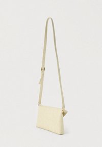 Μπεζ τσάντα ώμου με υφή επιφάνειας σε σχέδιο ερπετού, επίπεδο σχήμα και μακρύ, ρυθμιζόμενο λουράκι. Διακοσμητικά στοιχεία σε χρυσό τόνο.