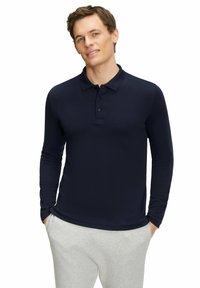 Marineblaues Langarmpolo mit Kragen und drei Knöpfen, aus glattem Stoff, kombiniert mit hellgrauen Jogginghosen.