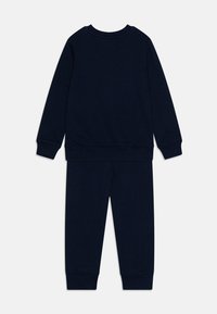 Chándal de algodón azul marino que incluye una sudadera de manga larga con puños de canalé y pantalones con cintura y puños elásticos.